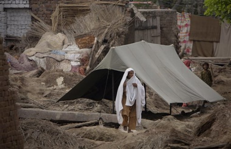 A Pakistani flood survivor walks amid of rubble of her house near Peshawar, Pakistan on Monday. Thousands of people streamed back to this historic southern city Monday where new levees hastily built from clay and stone held back floodwaters that have inundated much of Pakistan.